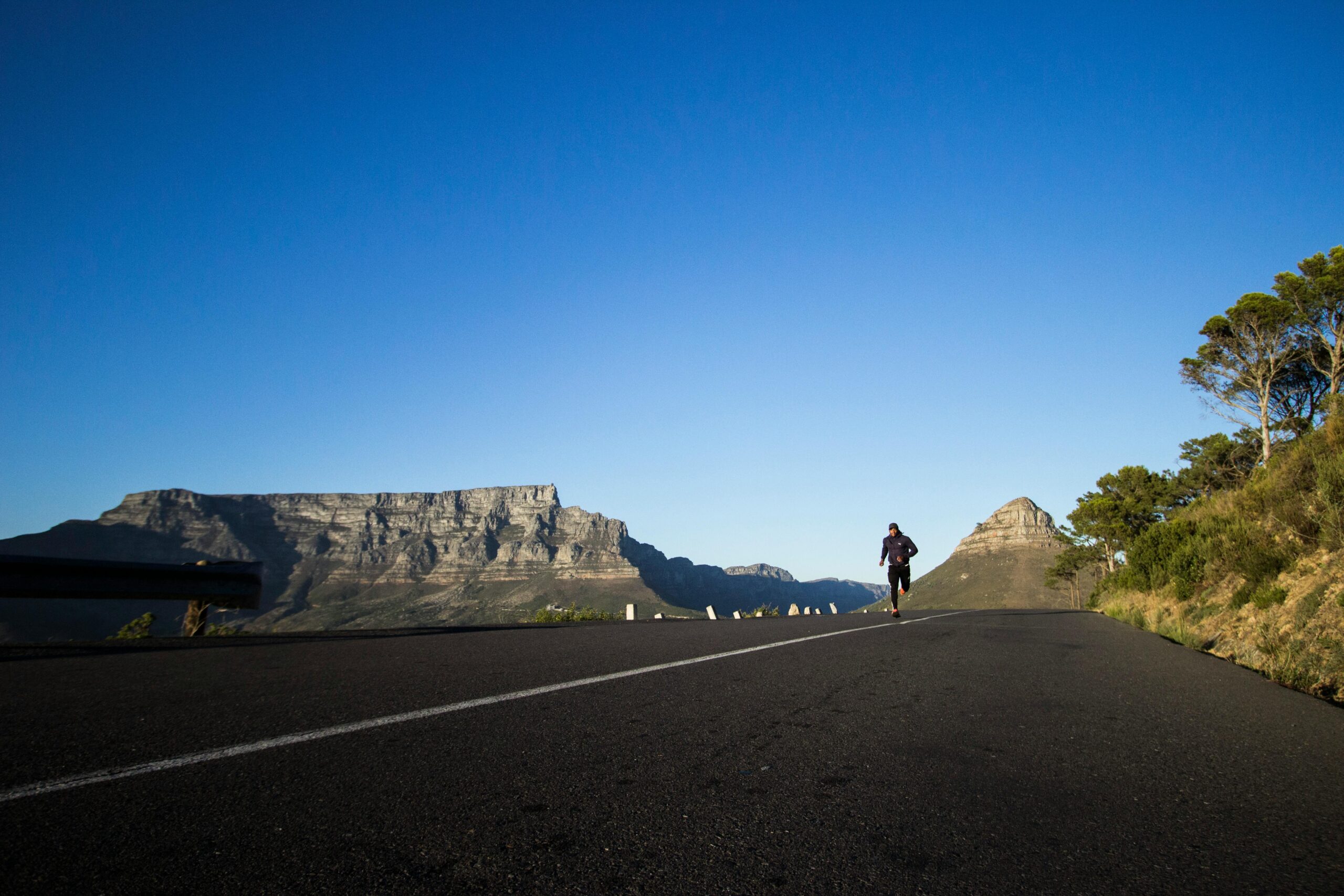 Man jogging along a scenic road with Table Mountain view in Cape Town.